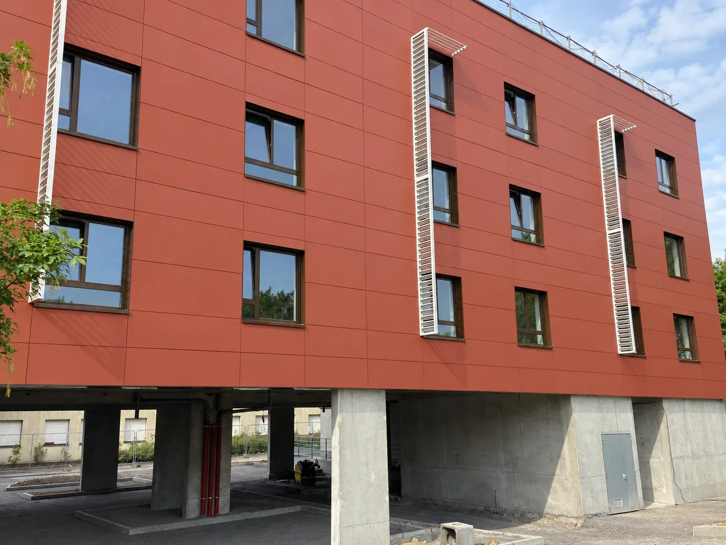 Façade en panneaux rouges avec brise-soleil blancs et piliers en béton du centre de rééducation l'Espoir
