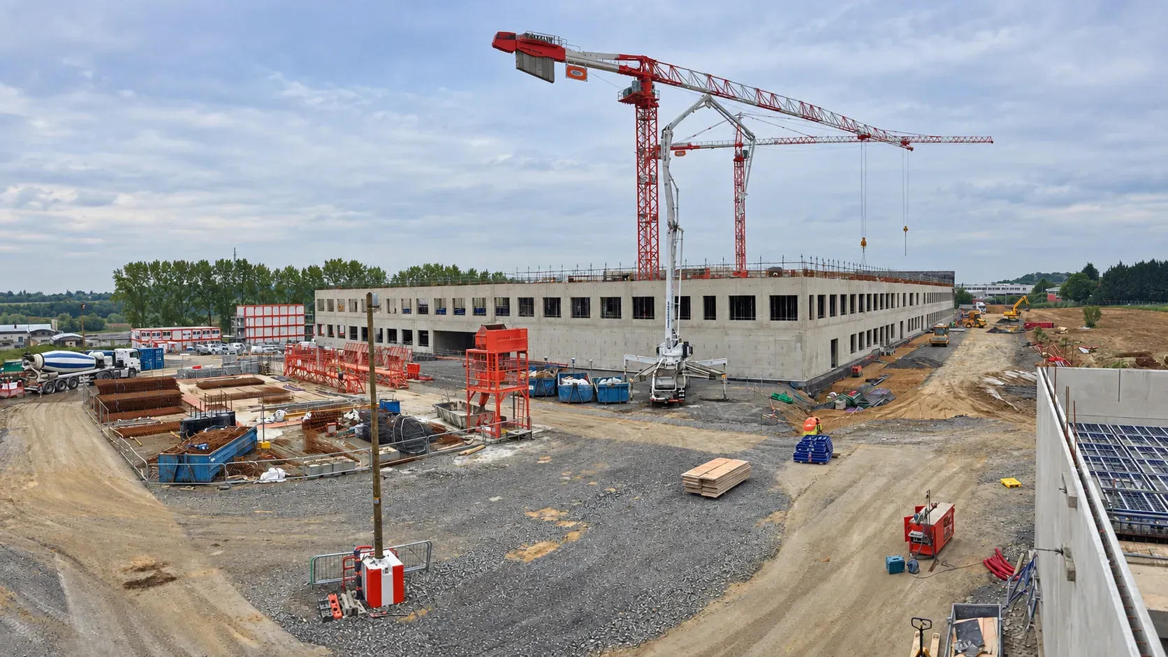 Vue d'ensemble du chantier de l'hôpital Sambre Avesnois à Maubeuge, grues rouges et bâtiment en béton