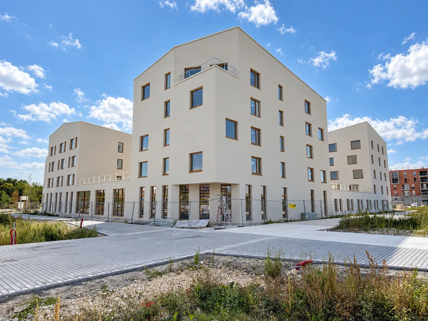 Hôtel hospitalier à Amiens terminé, façade enduite claire et menuiseries bois sous un ciel bleu