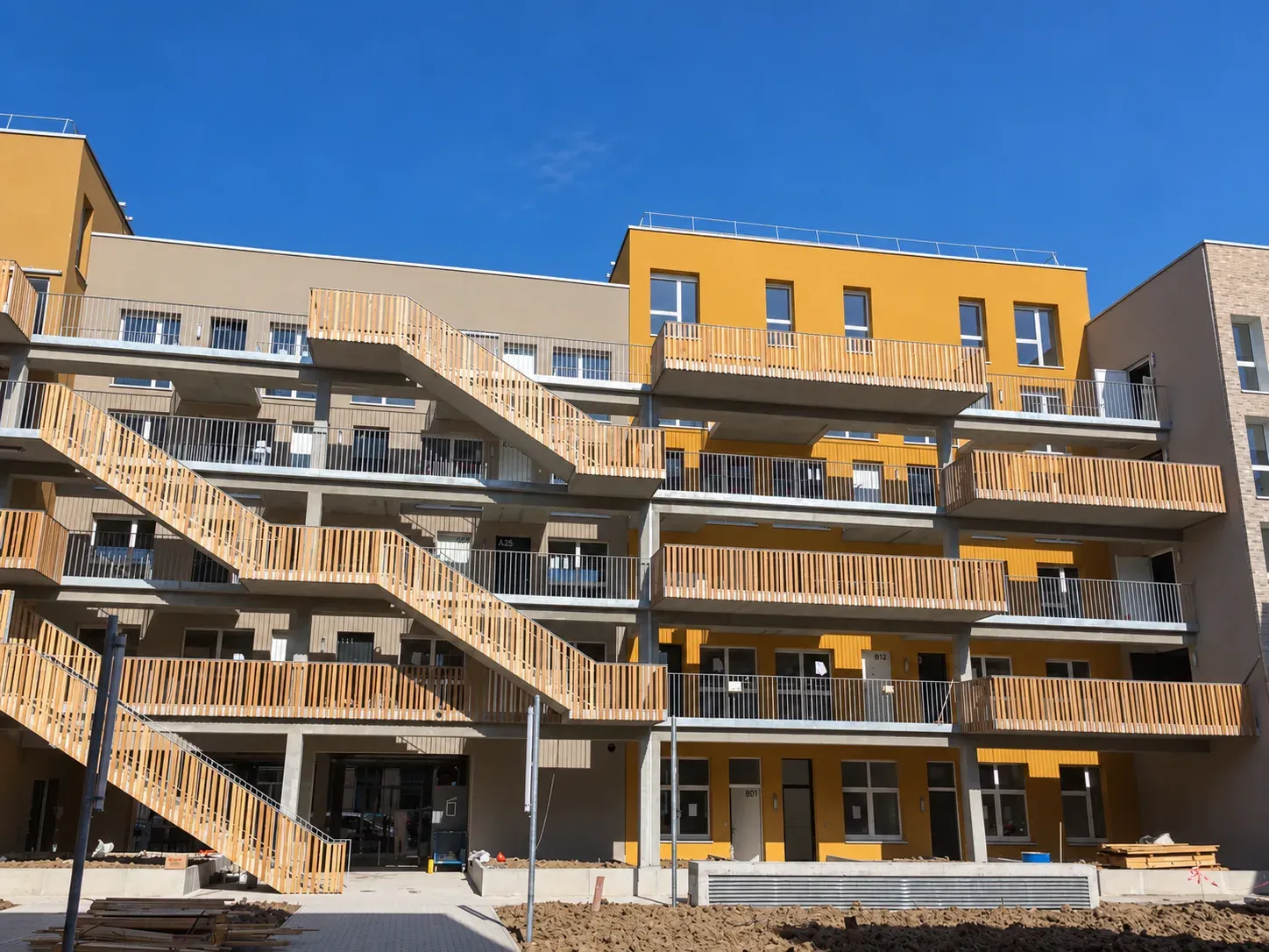 Ensemble de logements collectifs à Lille Wazemmes, façades jaune et beige avec coursives et escaliers extérieurs en bois