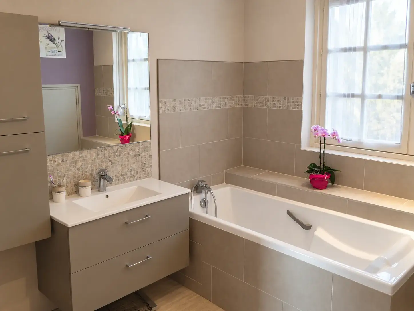 Salle de bain rénovée avec baignoire, meuble vasque suspendu et faïence beige