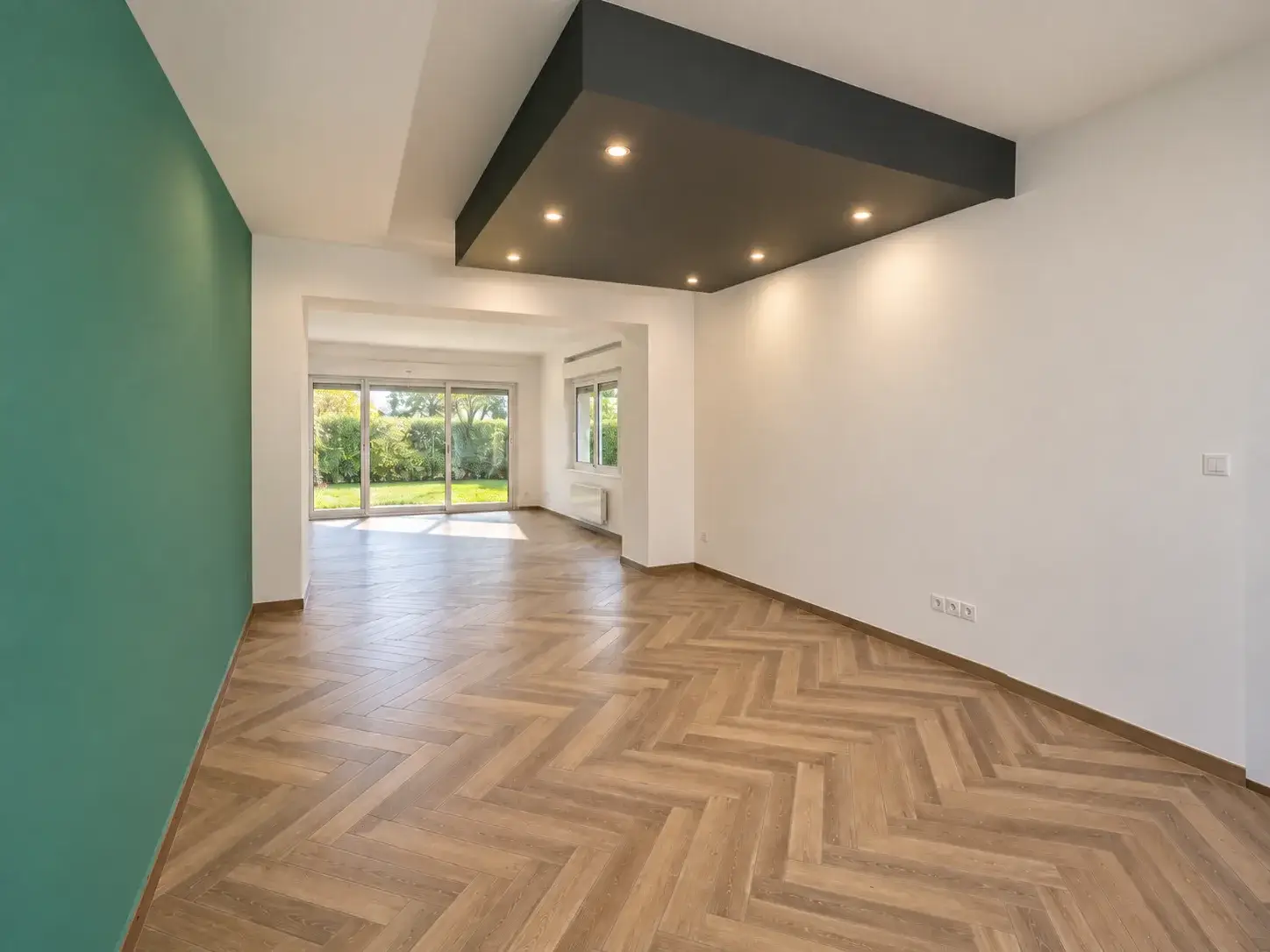 Salon cinéma avec plafond suspendu gris anthracite, spots encastrés et sol effet parquet à chevrons