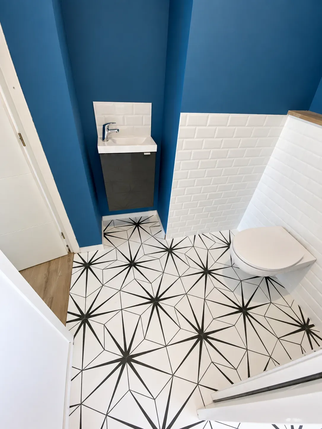 Lave-mains suspendu, faïence blanche et carrelage graphique dans des toilettes rénovées
